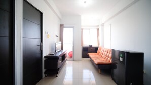 A modern room with a dark wardrobe, a desk with a computer, a sofa, and a window with curtains. - Simple 2Br With Extra Bed At Menara Rungkut Apartment (Surabaya)