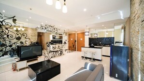 A modern living room with a flat-screen TV, a black coffee table, and a grey sofa.