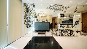 A modern living room with a flat-screen TV, a wooden accent wall, and decorative wall art.