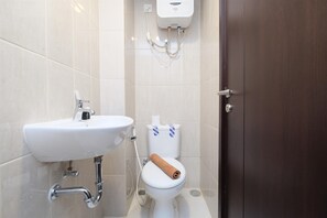 Une salle de bain avec un lavabo blanc, des toilettes et une pomme de douche.
