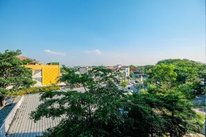 Une vue urbaine avec un bâtiment jaune imposant, des arbres verts et un ciel bleu dégagé.