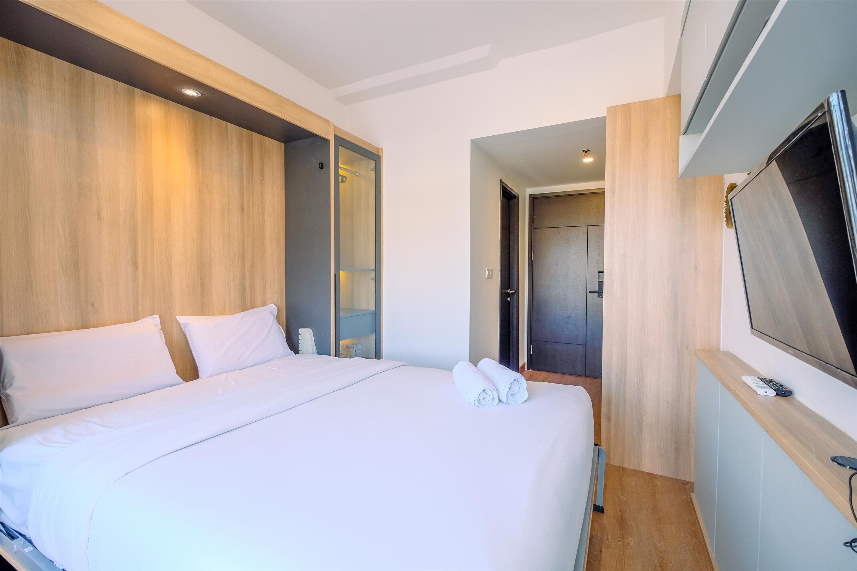 A hotel room with a large bed, a TV, and a wooden headboard.