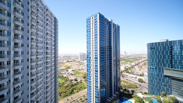 Ein hoch aufragendes Gebäude mit modernem Design, das mehrere Balkone und eine Glasfassade aufweist.