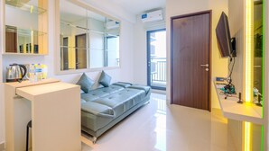 Habitación de hotel moderna con sofá, una mesita, un espejo y televisor montado en la pared.