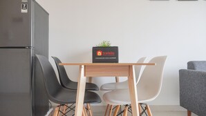 Una cocina compacta con refrigerador, una mesa de madera con sillas y una pequeña planta en maceta.