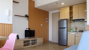 A modern kitchen with wooden cabinets, a stainless steel refrigerator, and a built-in TV. - Spacious And Cozy Studio Tokyo Riverside Pik 2 Apartment (Jakarta)