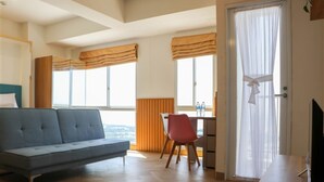 A modern hotel room with a sofa, a desk, and a TV. - Spacious And Cozy Studio Tokyo Riverside Pik 2 Apartment (Jakarta)