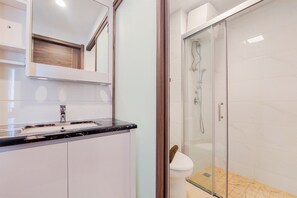 A modern bathroom with a glass-enclosed shower, a sink with a marble countertop, and a mirror above the sink. - Comfortable And Homey Living 2Br At Sky House Bsd Apartment (Pagedangan)