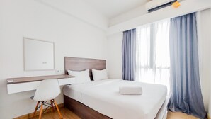 A hotel room with a bed, a desk, a chair, and a window with curtains. - Comfortable And Homey Living 2Br At Sky House Bsd Apartment (Pagedangan)