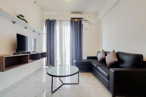 Uma sala de estar moderna com uma televisão de tela plana, uma mesa de centro de vidro, um sofá de couro preto e uma estante embutida.