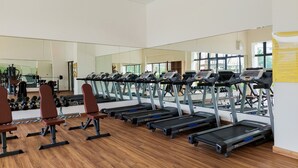 A gym with treadmills, weight benches, and a large mirror. - Comfortable And Homey Living 2Br At Sky House Bsd Apartment (Pagedangan)
