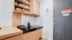 Een kleine keuken met houten kastjes, een zwart aanrecht, een spoelbak en een fornuis.