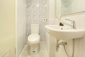Ein Badezimmer mit Toilette, Waschbecken und gefliesten Wänden.