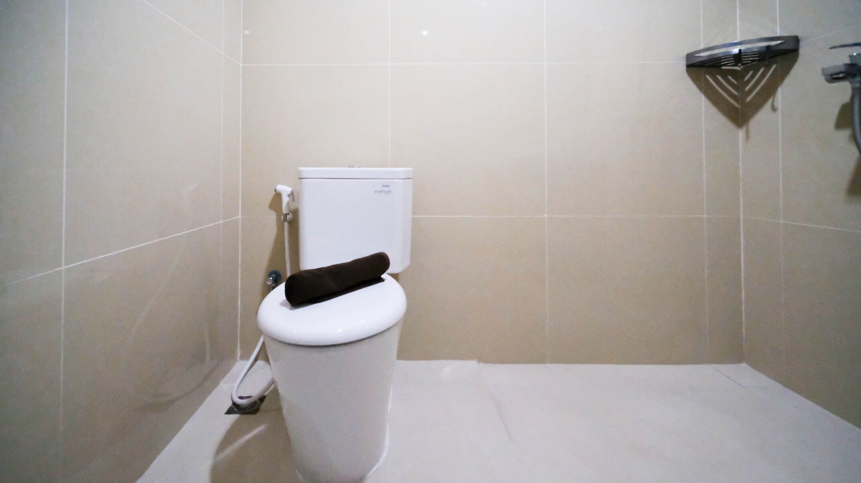 Une salle de bain équipée de toilettes, d’une douche et d’un sèche-mains fixé au mur.