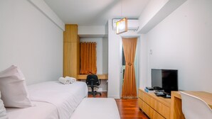A hotel room with two beds, a desk, a chair, a TV, and a wardrobe. - Simply Look Studio (No Kitchen) At Dramaga Tower Apartment (Dramaga)