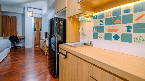 A compact hotel room with a kitchenette, a bed, a desk, and a wardrobe. - Simply Look Studio (No Kitchen) At Dramaga Tower Apartment (Dramaga)