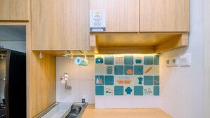 A kitchen with wooden cabinets, a stainless steel sink, and a backsplash with various food and kitchen item icons. - Simply Look Studio (No Kitchen) At Dramaga Tower Apartment (Dramaga)