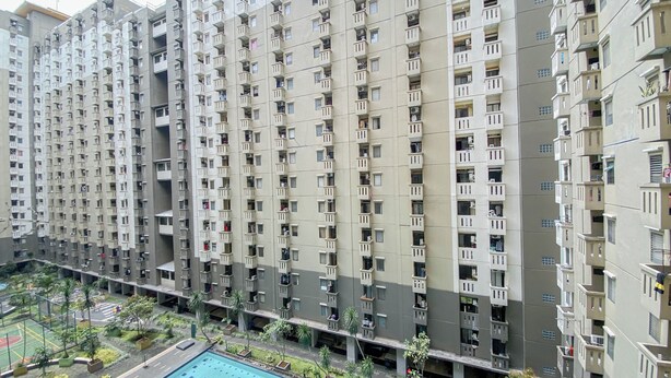 Un immeuble résidentiel de grande hauteur doté de nombreux balcons, d’une piscine et d’un espace paysager avec des arbres.