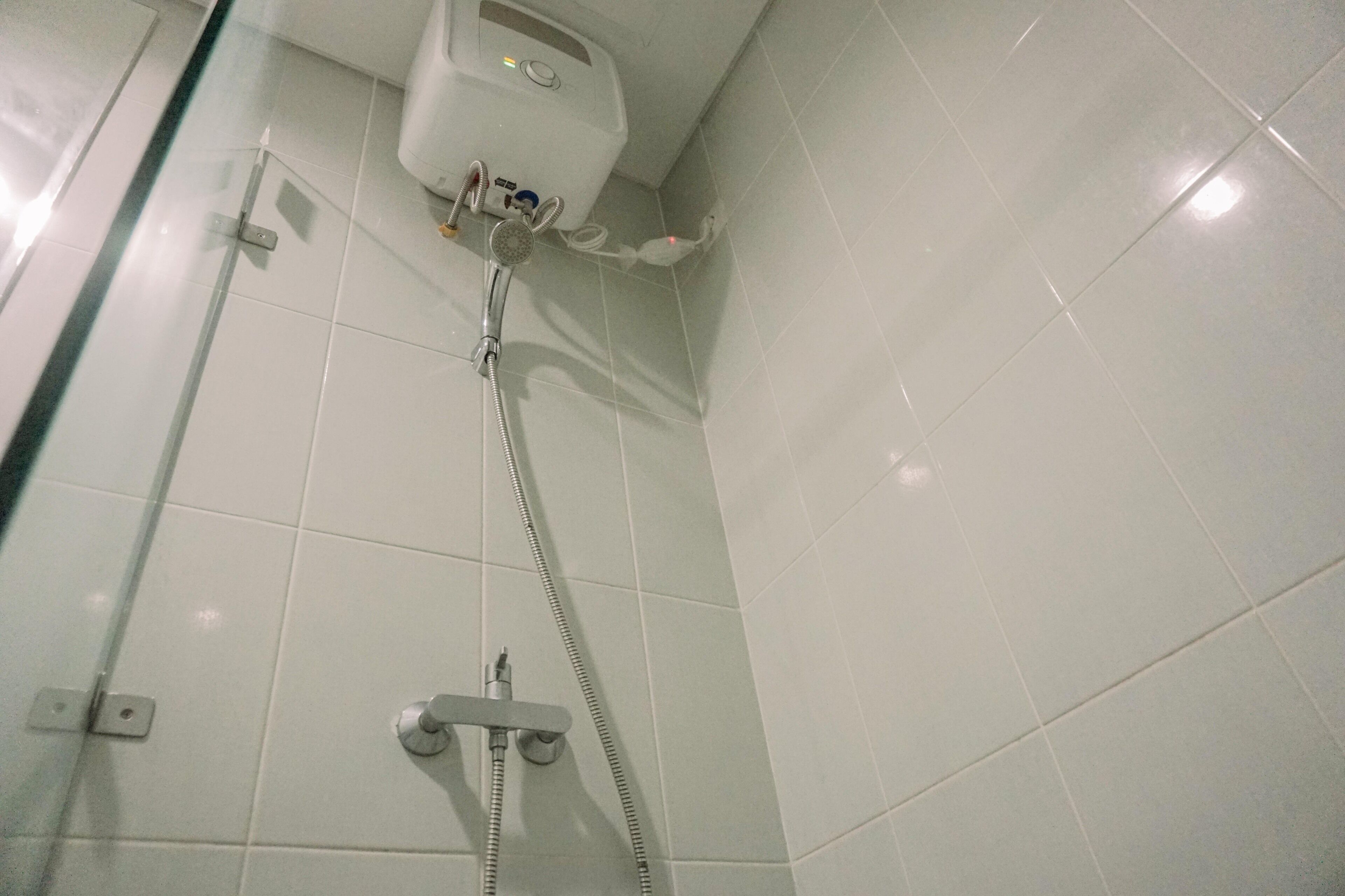 Une douche équipée d’un pommeau de douche à main et d’un panneau de commande fixé au mur.
