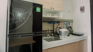 Eine Küche mit einem schwarzen Kühlschrank, einer Spüle und einer Arbeitsplatte mit verschiedenen Gegenständen.
