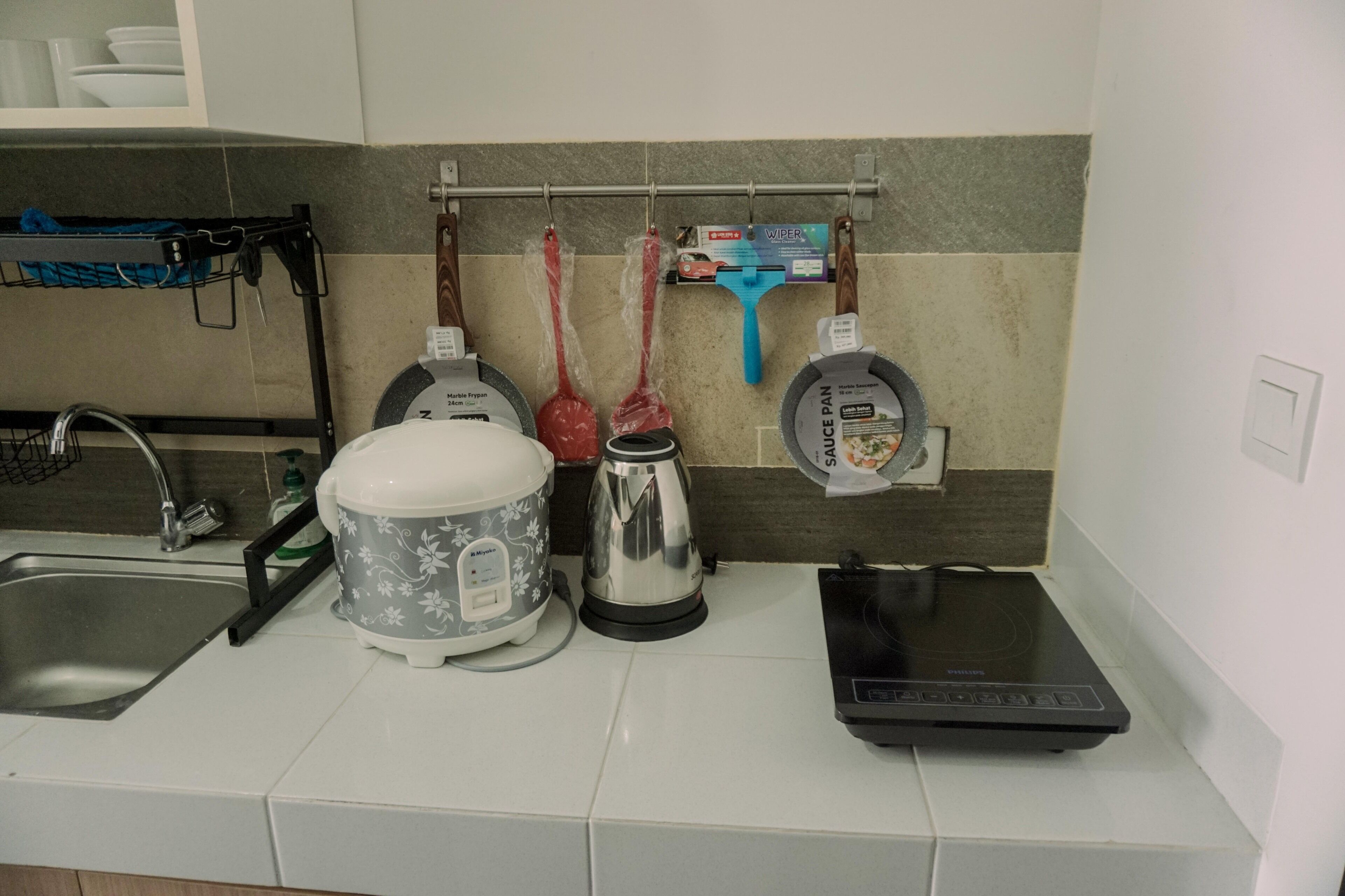Een keuken met een magnetron, waterkoker en rijstkoker op het aanrecht.
