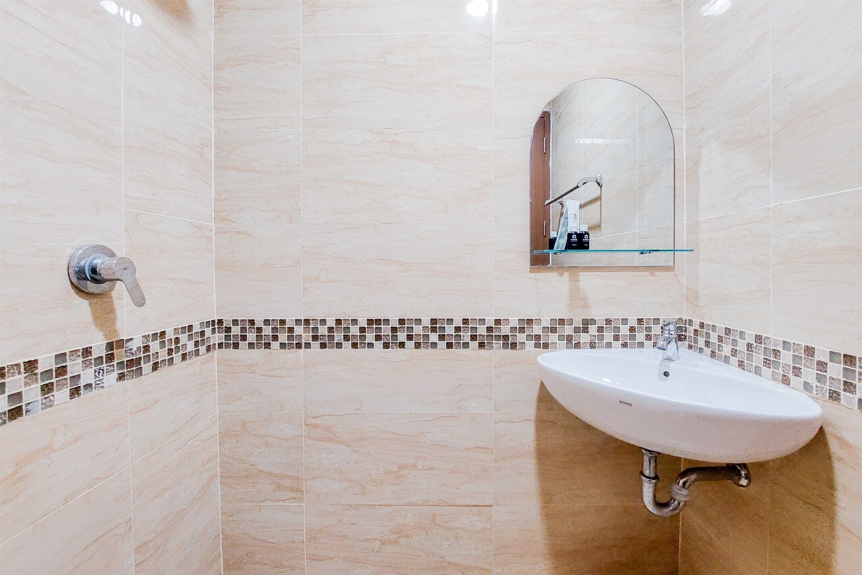 Casa de banho com lavatório, espelho e paredes revestidas a azulejos.