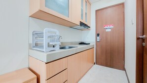 Une cuisine de taille réduite, dotée de meubles de rangement en bois, d’un four à micro-ondes encastré et d’un évier.