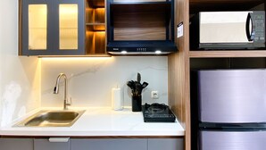 A modern kitchen with a stainless steel sink, a built-in oven, and a microwave. - Homey and Simply Look Studio LRT City Jatibening Apartment (Bekasi)