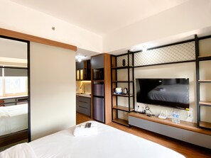 Ein Hotelzimmer mit Bett, Fernseher, Minibar und einem durchgegangenen Tür erkennbaren Badezimmer.