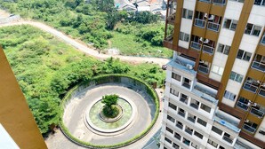 A high-rise building with multiple balconies and a circular park area with a central tree. - Homey and Simply Look Studio LRT City Jatibening Apartment (Bekasi)