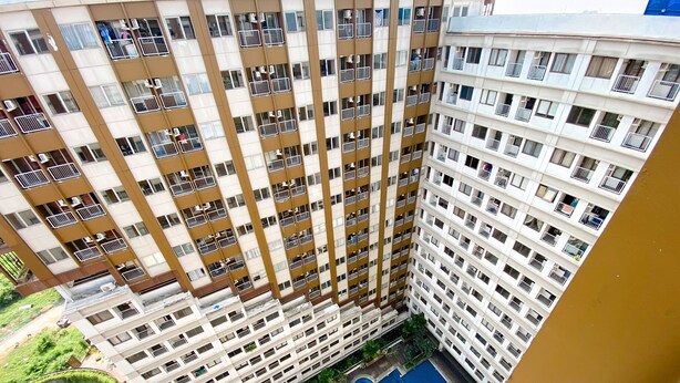 A high-rise building with multiple balconies and a central courtyard with a swimming pool. - Homey and Simply Look Studio LRT City Jatibening Apartment (Bekasi)