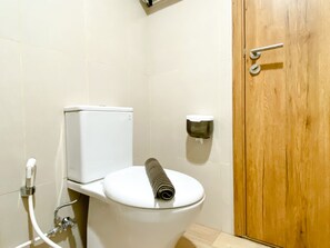 Ein Badezimmer mit Toilette, Papierhandtuchspender und Holztür.
