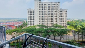 A high-rise building with multiple floors and balconies, surrounded by greenery and other buildings. - Warm And Enjoy Living Studio Casa De Parco Apartment (South Tangerang)