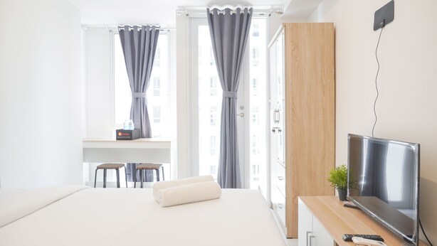 Ein Hotelzimmer mit einem Bett, einem Schreibtisch mit Stuhl, einem Fernseher und einer kleinen Pflanze.