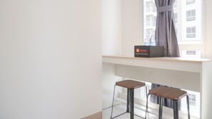 Ein modernes Zimmer mit Fenster, einem kleinen Tisch und zwei Barhocker.