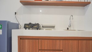 A kitchen with a built-in stove, a sink, and wooden cabinets. - Simply Look Studio Tokyo Riverside Pik 2 Apartment (Teluknaga)