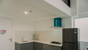 A modern kitchen with a black refrigerator, a gas stove, and a teal hood vent. - Exclusive And Homey 3Br Loft At Kingland Avenue Apartment (South Tangerang)