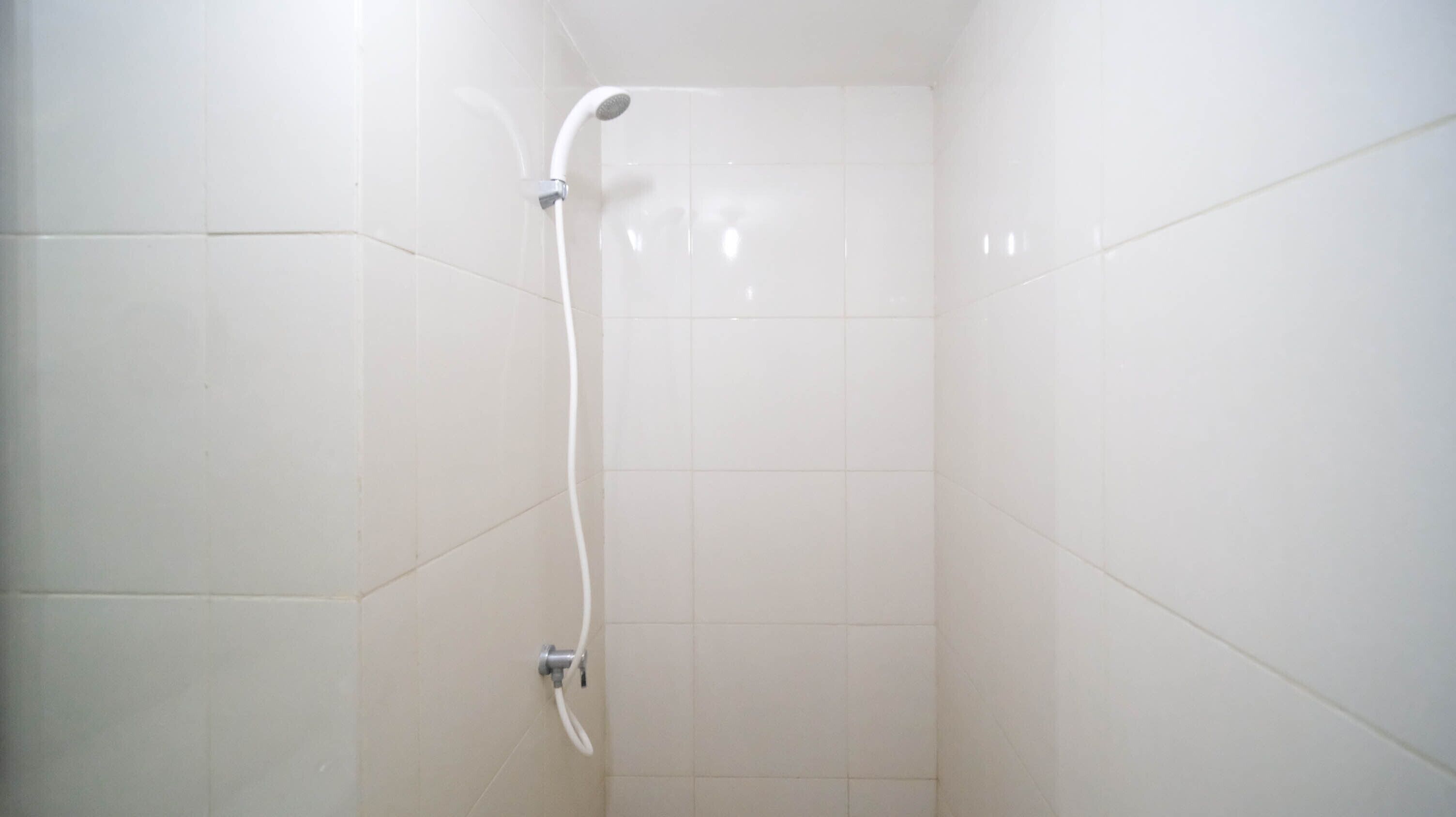 Una ducha con cabezal de ducha de mano y grifería empotrada en la pared.
