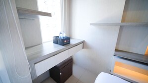 A small, modern room with a desk, a chair, a window with curtains, and a bedside table with a lamp. - Nice Studio Connected To Mall At Tanglin Supermall Mansion Apartment (Surabaya)