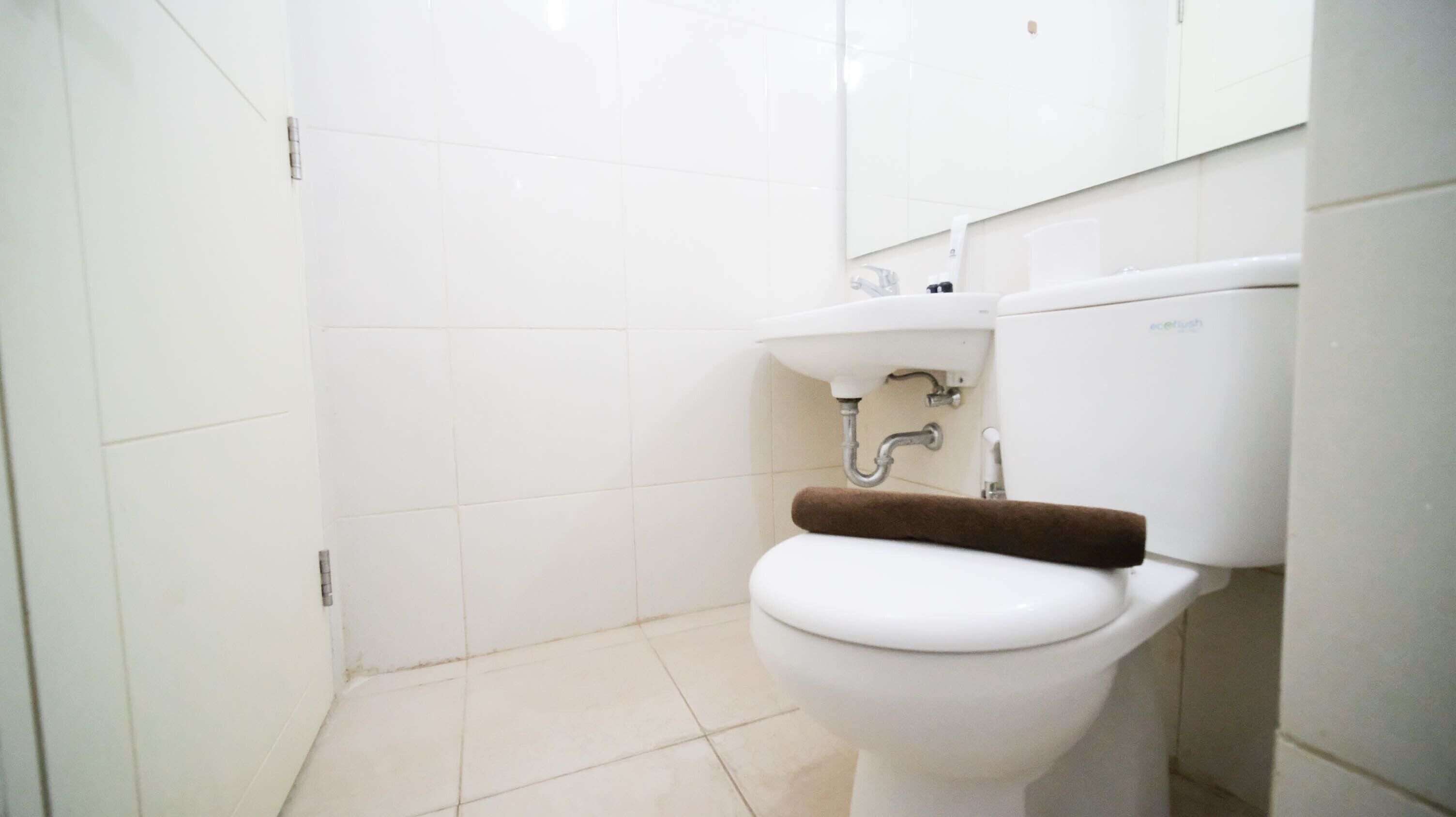 A small, clean bathroom with a toilet, sink, and white tiles.