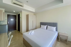 Habitación de hotel con cama, mesita de noche, armario y baño visible a través de una puerta abierta.