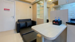 Une chambre d’hôtel moderne équipée d’un canapé, d’une petite table, d’un minibar et d’une vitrine.