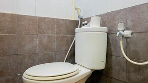 Des toilettes équipées d’un réservoir de la marque TOTO et d’un pommeau de douche.