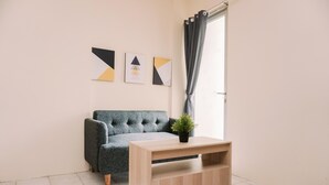 A living room with a grey sofa, a wooden coffee table, and a potted plant. There are three framed artworks on the wall. - Comfort Designed 2Br Apartment At Mediterania Palace Residence (Jakarta)