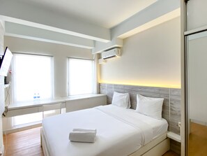 Ein modernes Hotelzimmer mit einem großen Bett, integriertem Schreibtisch und Blick auf die Stadt.