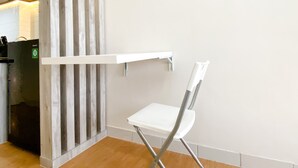 A white chair with a metal frame, a white shelf, and a wooden floor. - Modern Look And Comfy Studio Patraland Urbano Apartment (Bekasi)