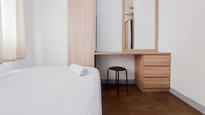 Un dormitorio con una cama, un escritorio de madera, una silla y un espejo.