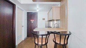 Una cocina compacta con encimera de madera, dos sillas negras y una puerta blanca.