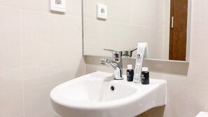 A white bathroom sink with a chrome faucet, a mirror above it, and two bottles of Ravello dental kit on the sink. - Wonderful And Homey Studio Vasaka Solterra Apartment (Jakarta)