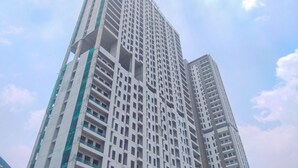 Ein Hochhaus mit mehreren Etagen und Balkonen, unter einem teils bewölkten Himmel.